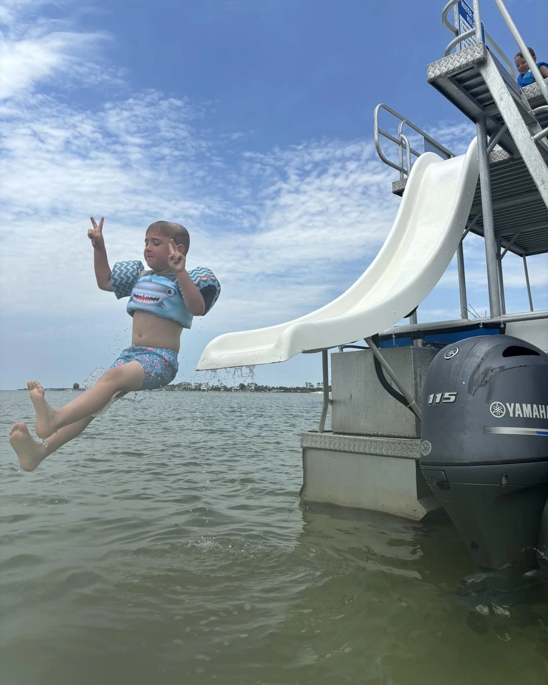 child sliding down slide off the back of a double decker slide pontoon boat in port st. joe